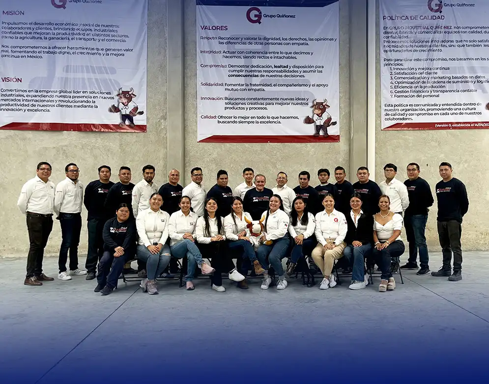 Fotografía del equipo completo de Básculas Quiñonez posando en sus instalaciones frente a los carteles de Misión, Visión y Valores de la empresa